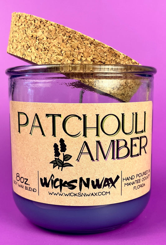Recycled glass candle in clear jar with purple wax and cork lid, side view.