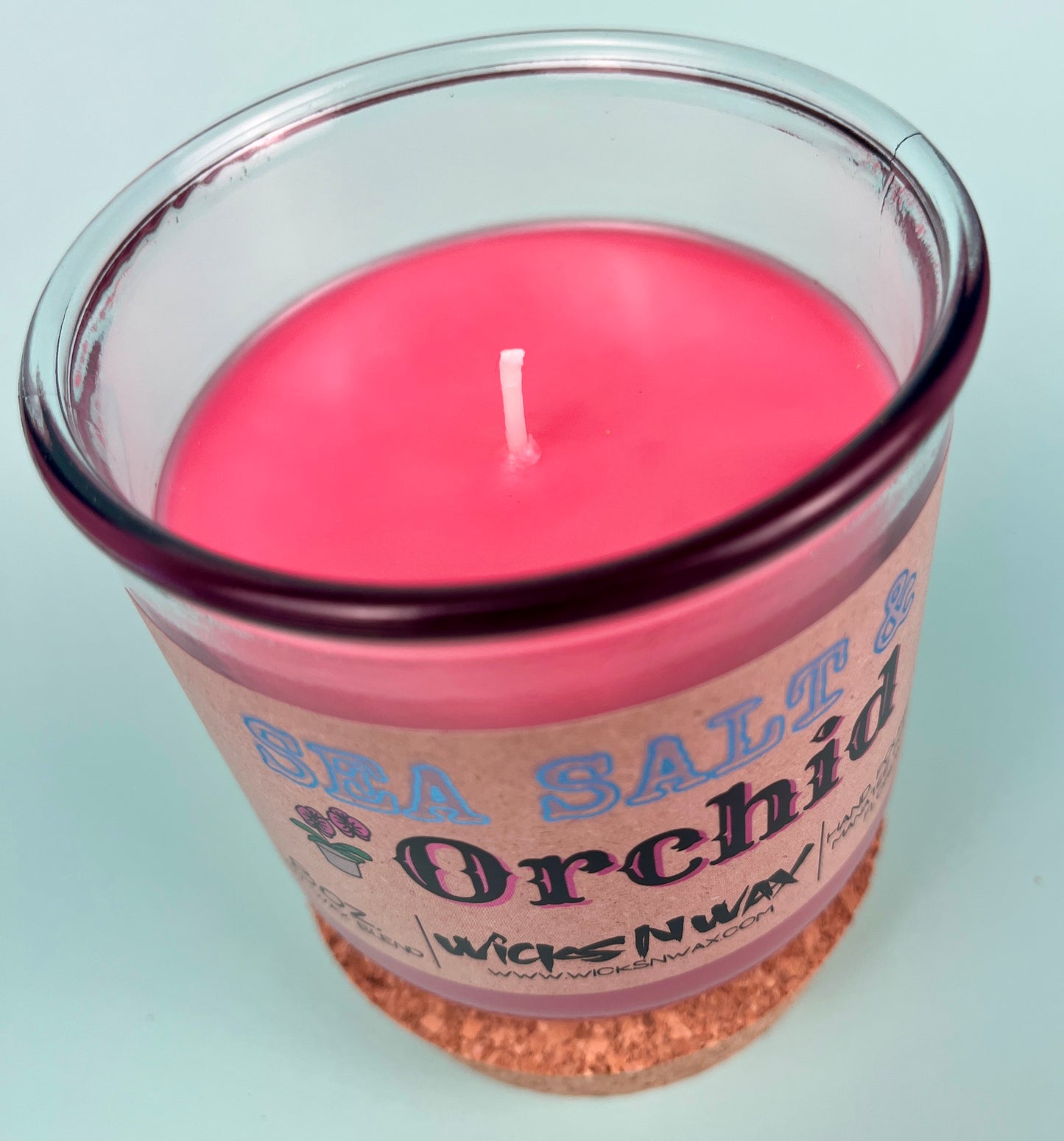 Recycled glass candle with pink wax, centered wick, cork base visible