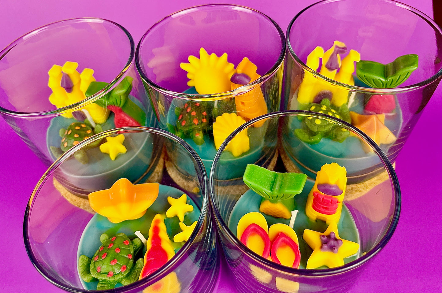 Small scented candle set in clear glass jars with assorted colorful wax shapes