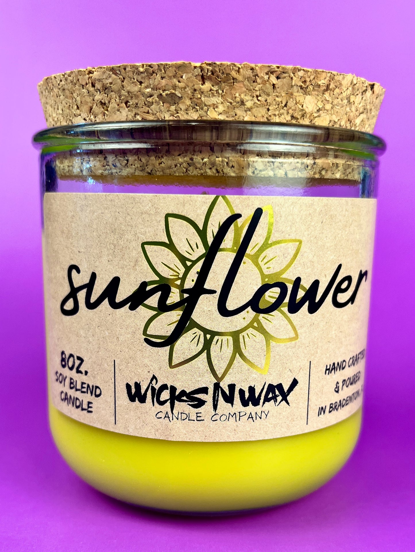 Recycled glass candle with sunflower label and yellow wax in clear jar