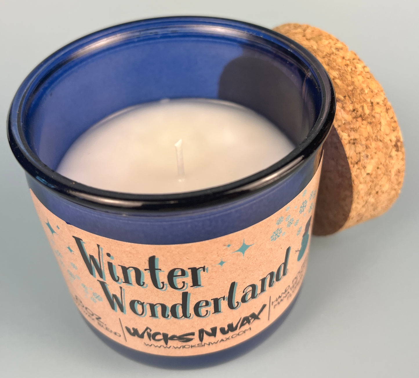 Blue glass candle with white wax pool and wick, Winter Wonderland label
