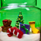 Christmas art candle with white wax and molded holiday figures in a clear glass jar