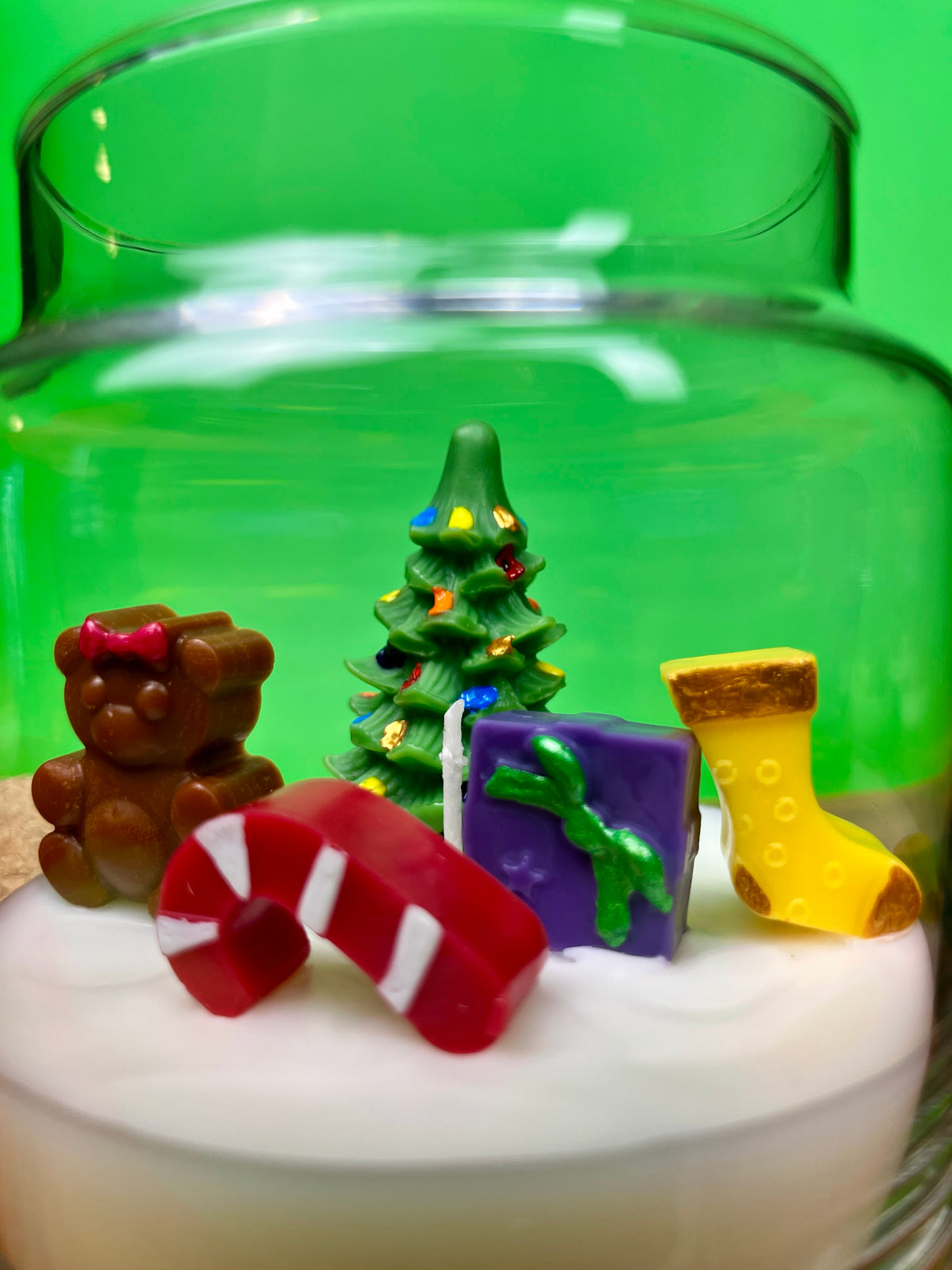 Christmas art candle with white wax and molded holiday figures in a clear glass jar