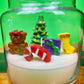 Christmas art candle in a clear jar, with a decorated tree, teddy bear, candy cane and stocking