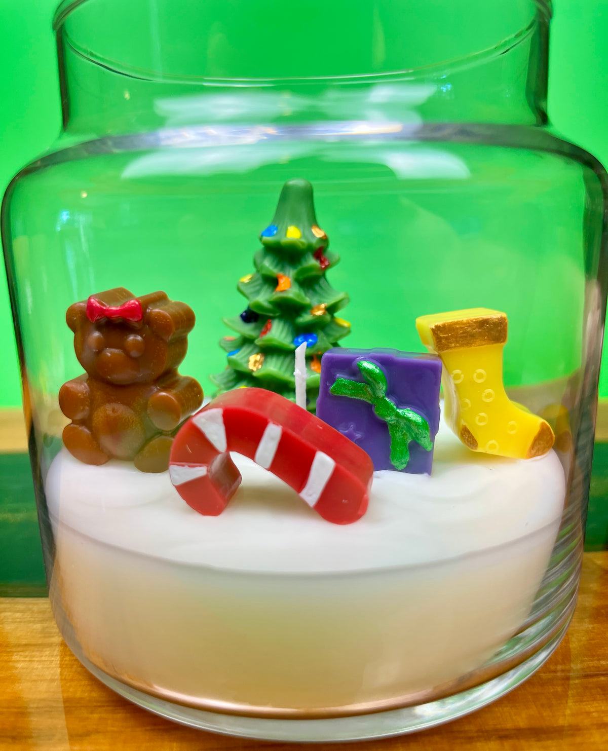 Christmas art candle in a clear jar, with a decorated tree, teddy bear, candy cane and stocking