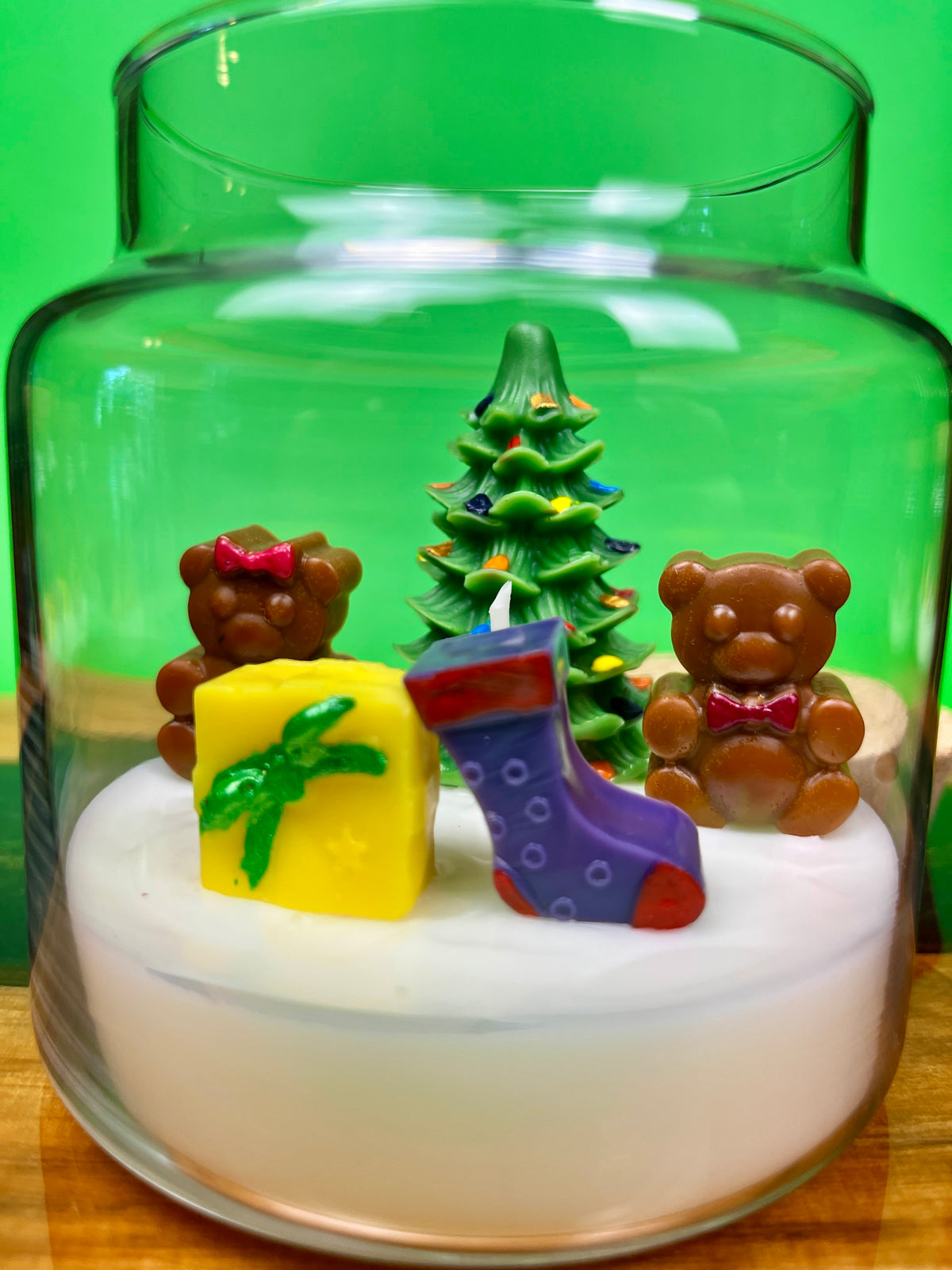 Christmas art candle with a tree, two teddy bears, gift and stockings in white wax