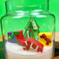 Christmas art candle with a decorated tree, candy cane, stocking and gift figures