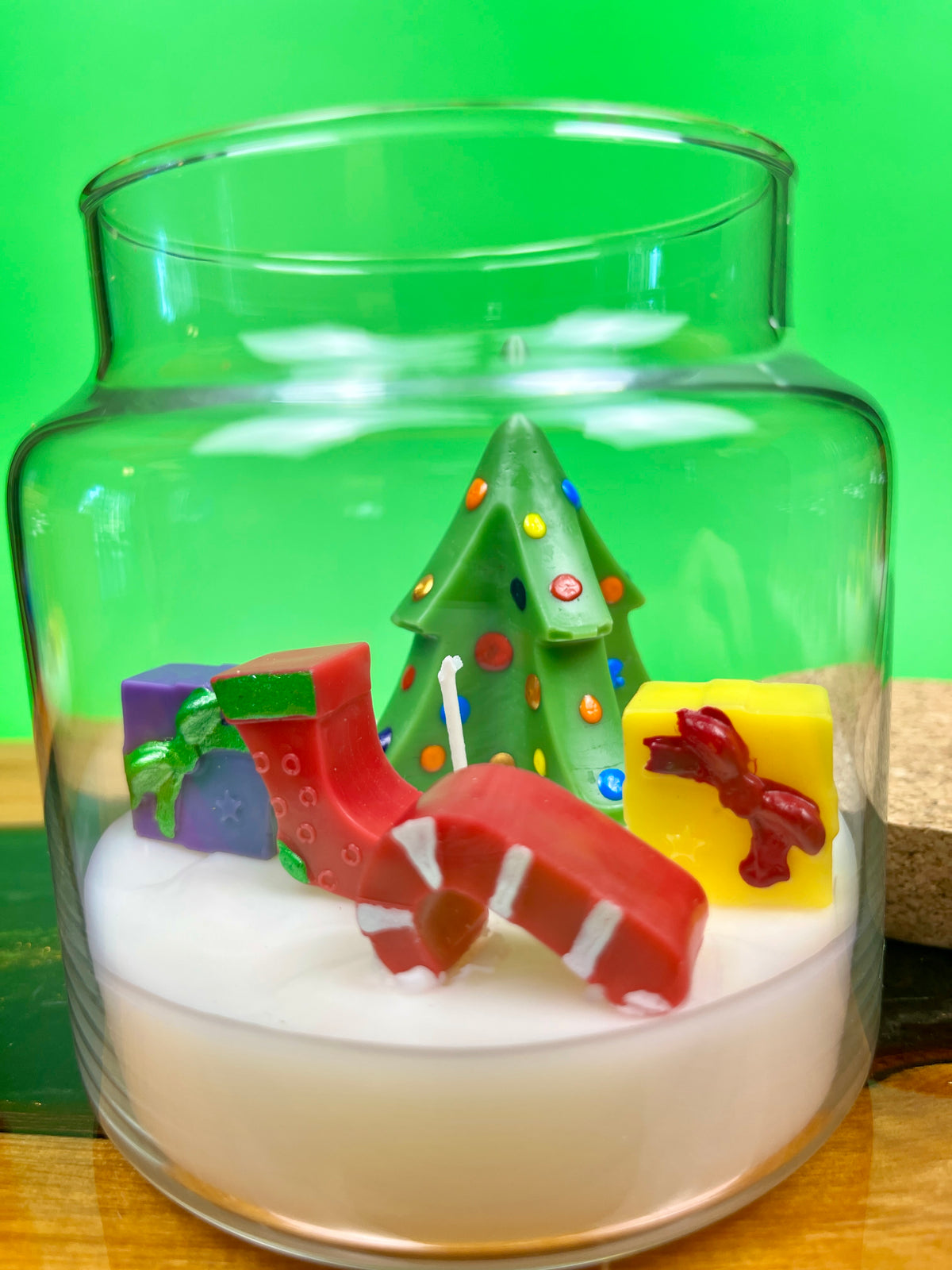 Christmas art candle with a decorated tree, candy cane, stocking and gift figures