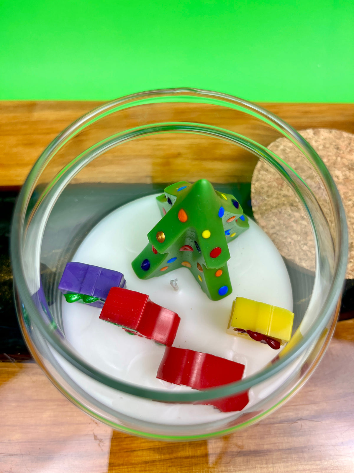 Christmas art candle viewed from above, with a molded tree and colorful wax shapes