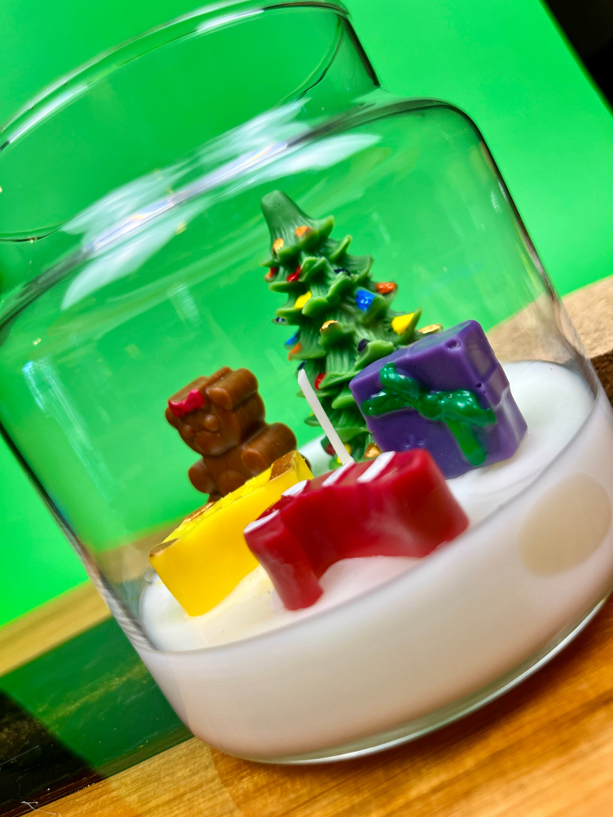 Christmas art candle in a tilted clear jar, with white wax and colorful holiday figures
