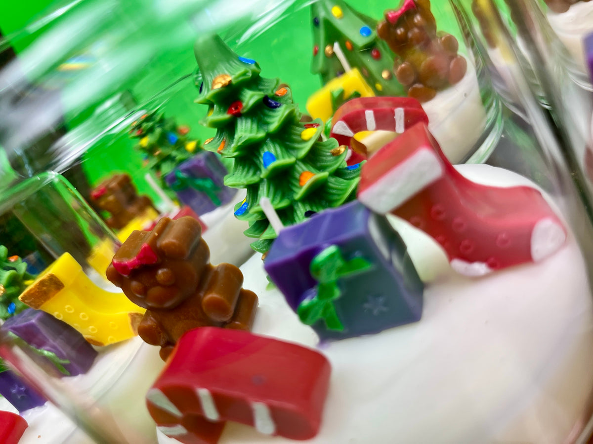 Christmas art candle in a glass jar, with white wax and colorful molded holiday decorations