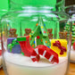 Christmas candle in a glass jar with a decorated tree, gifts, and candy cane embeds