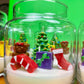 Christmas candle in a glass jar with a tree, teddy bears, gifts, and stocking embeds