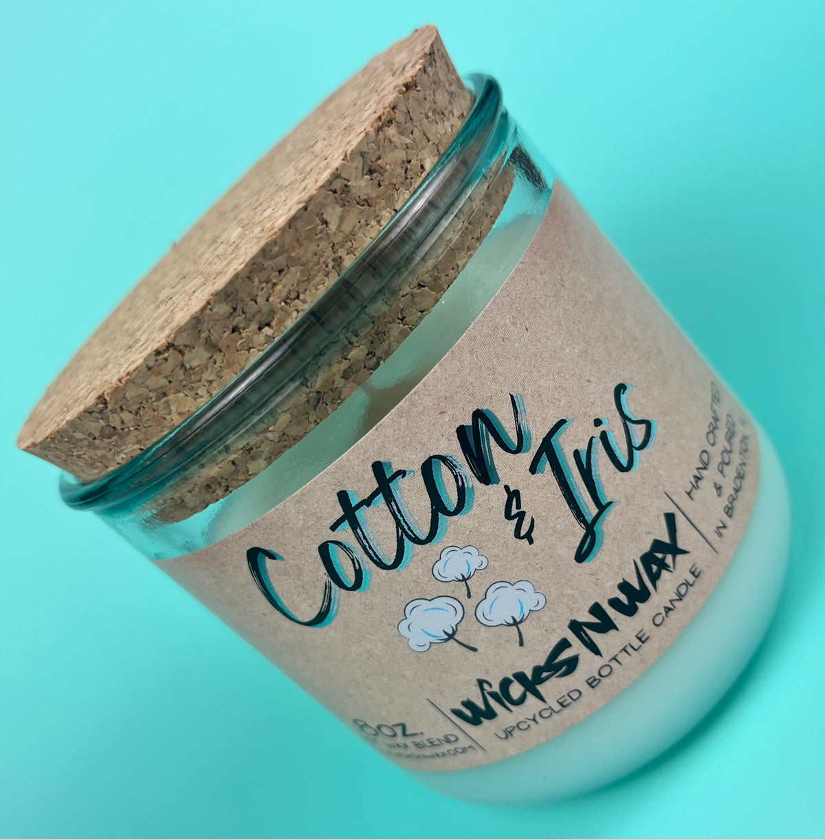 Recycled glass candle with cork lid, kraft label and “Cotton & Iris” logo, angled
