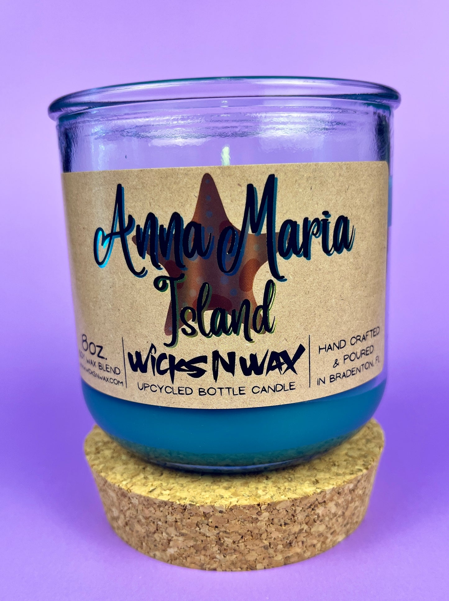 Recycled glass candle with blue wax, beige label, and cork lid plus cork coaster