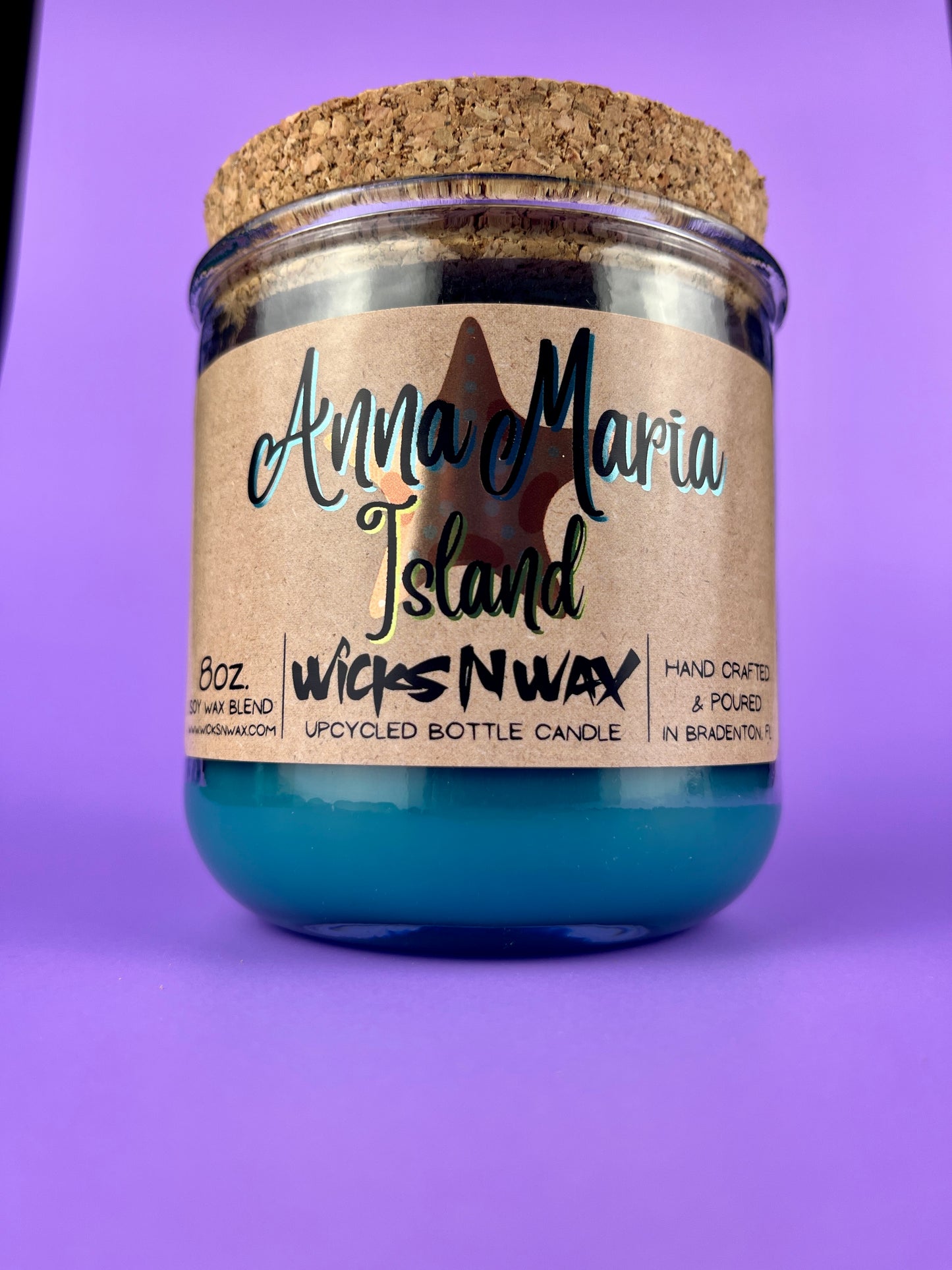 Recycled glass bottle candle with blue wax, beige label, and cork lid on top