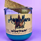 Recycled glass candle with blue wax, beige label, and cork lid tilted behind