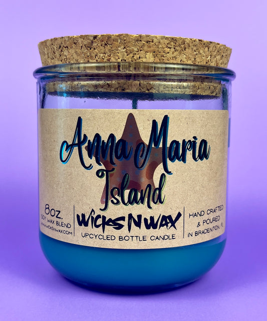 Recycled glass bottle candle with blue wax and beige label, cork lid on top