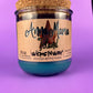 Recycled glass bottle candle with blue wax, beige label, and cork lid on top