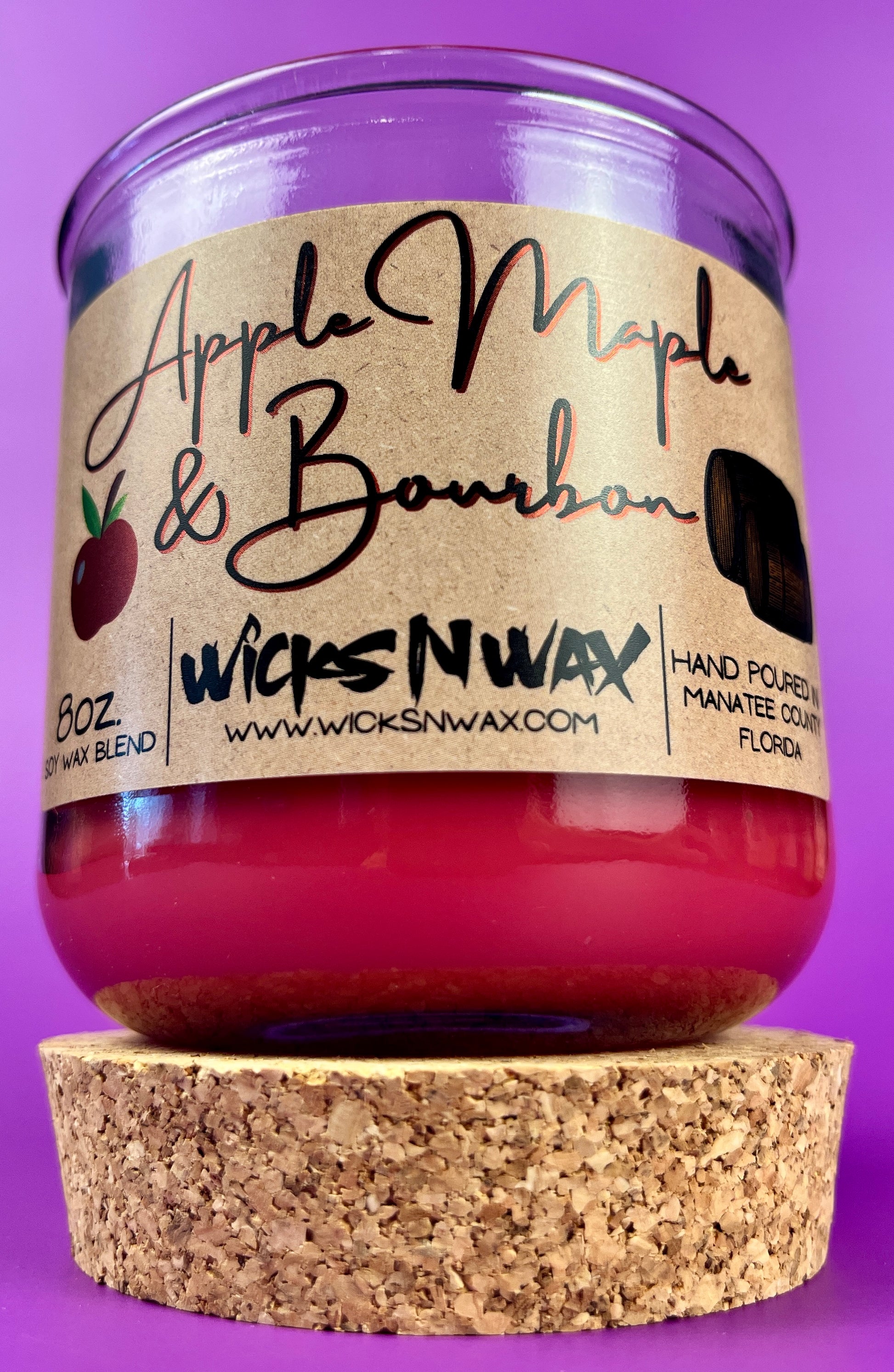 Recycled glass candle with red wax and Apple Maple & Bourbon label, cork base