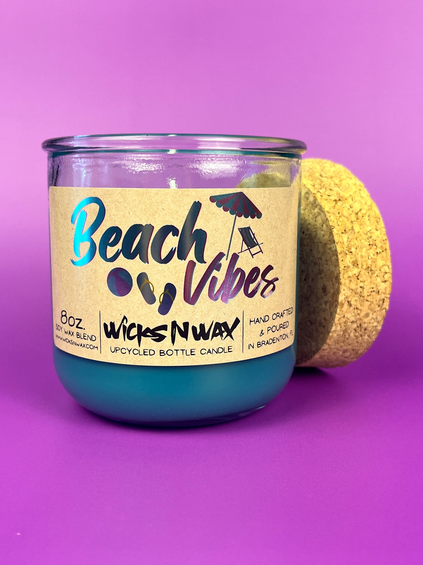Recycled glass candle with blue wax, clear jar, cork lid on side, beach-themed label