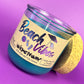Recycled glass candle with blue wax, clear jar, cork base, tilted beach-themed label