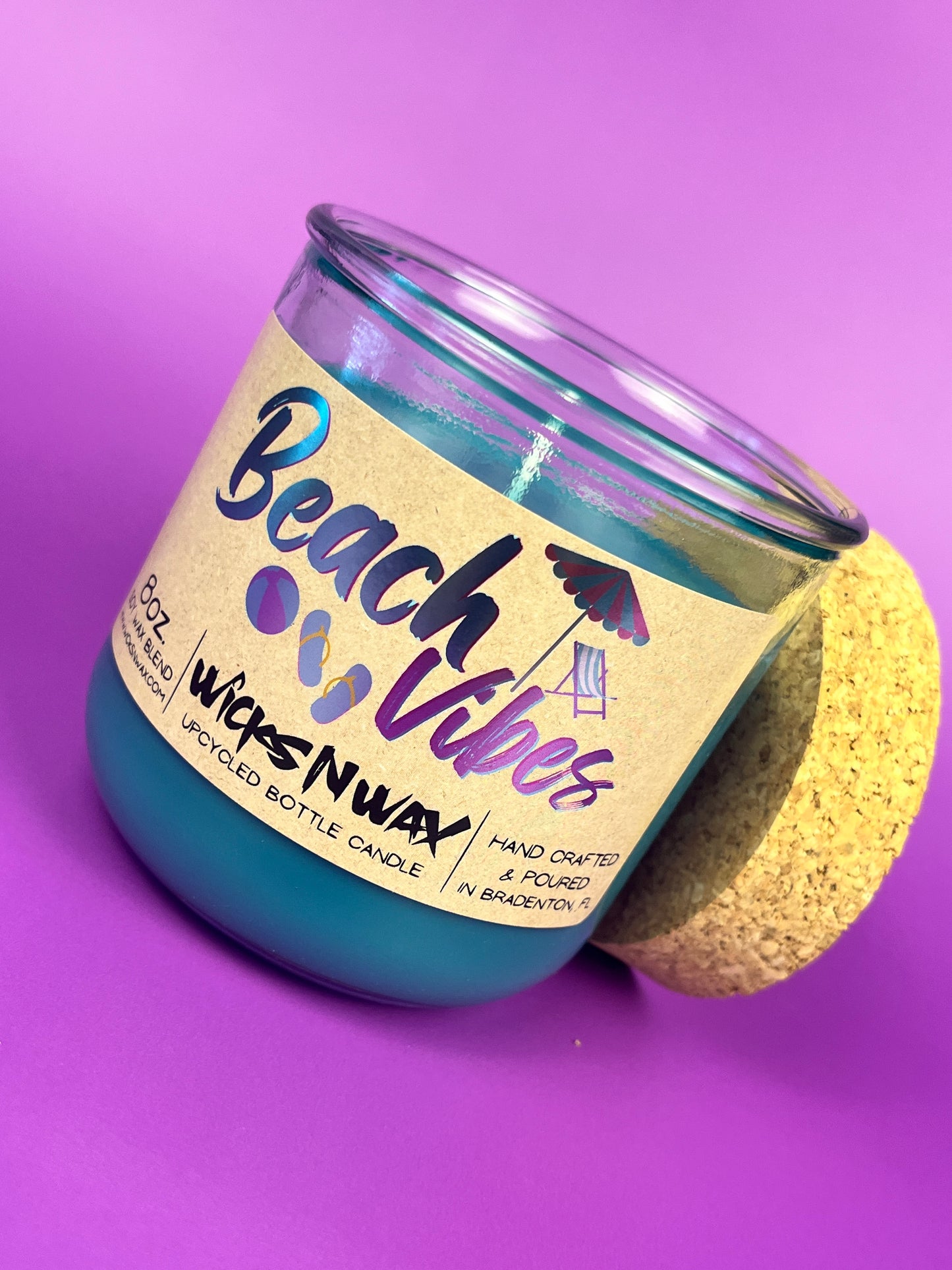 Recycled glass candle with blue wax, clear jar, cork base, tilted beach-themed label