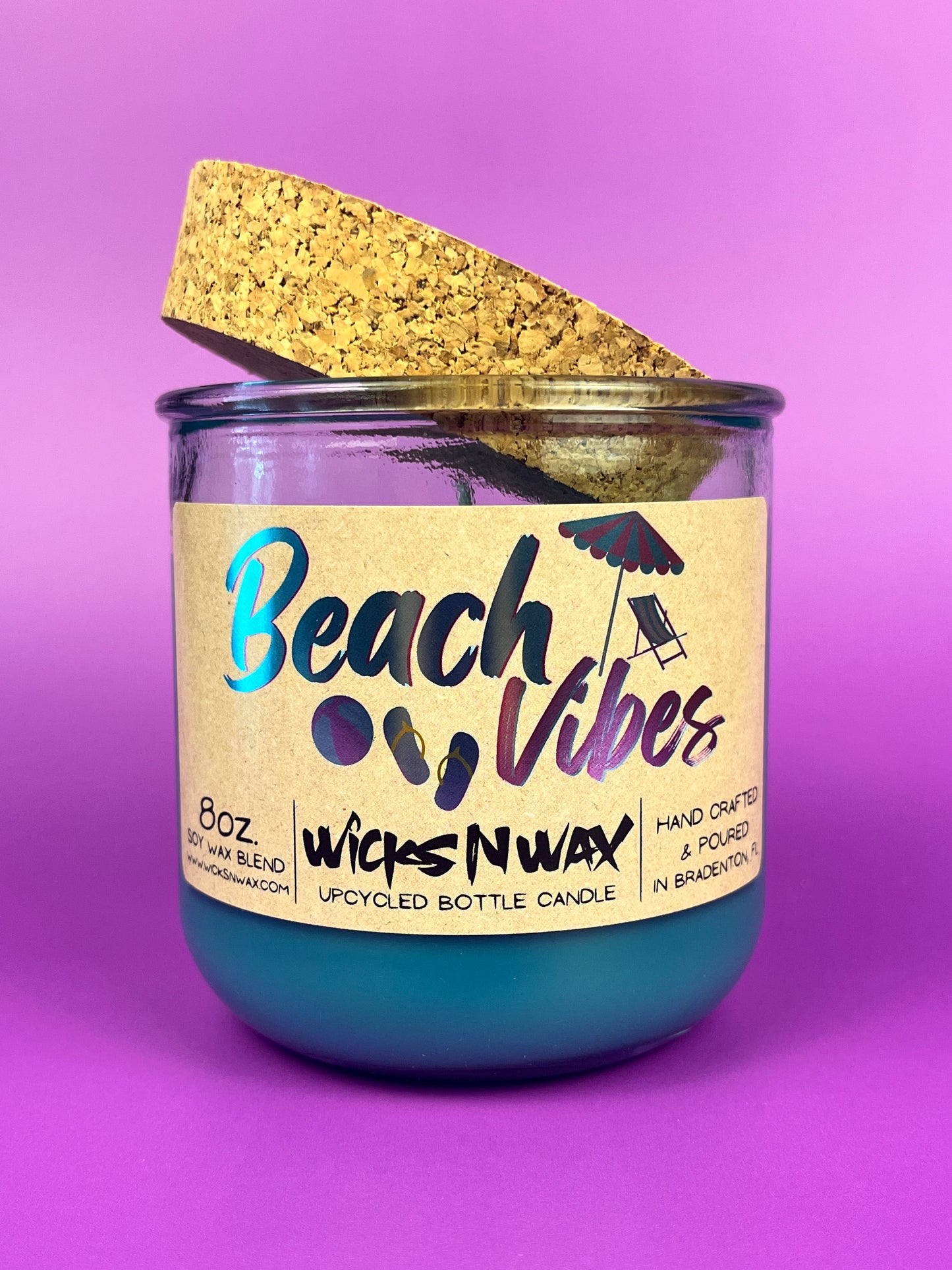 Recycled glass candle with blue wax, clear jar, cork lid piece, beach-themed label