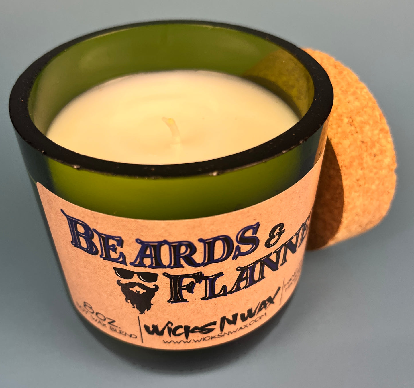 Dark green candle jar with Beards & Flannel label; cream wax top visible
