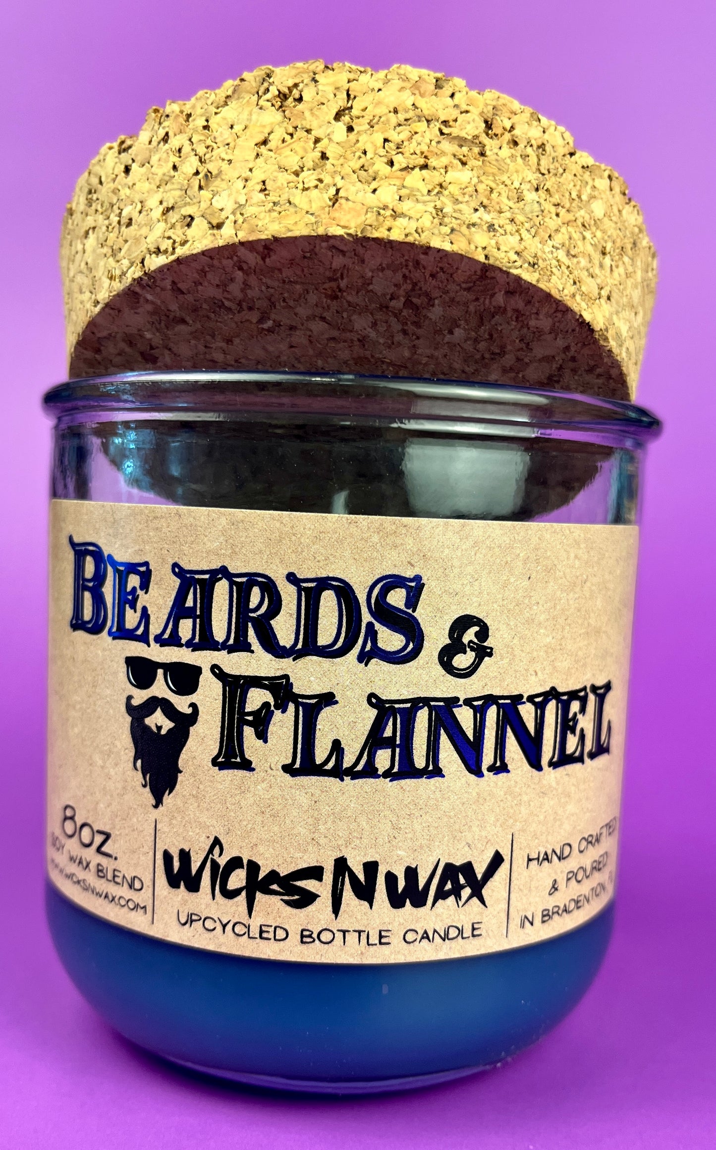 Blue recycled glass candle with cork lid, front label and branding visible.