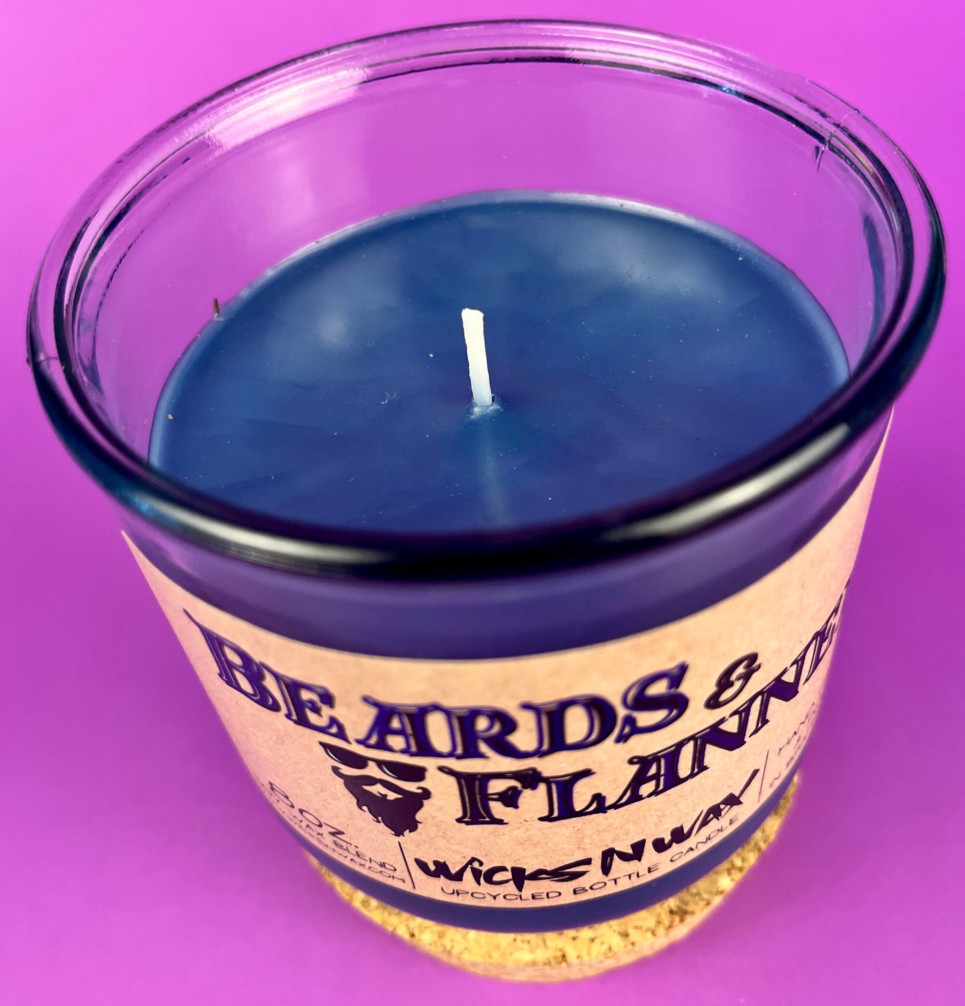 Blue candle in glass jar with wick visible; label reads "Beards & Flannel".