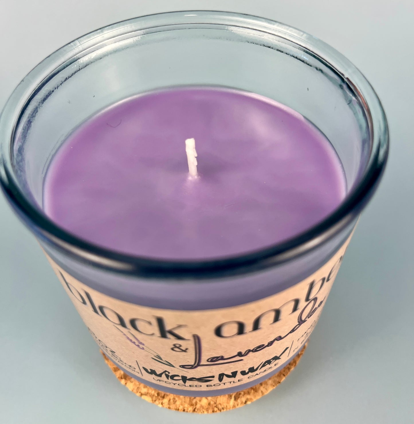 Recycled glass candle with visible white wick; purple wax inside jar