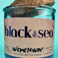 Recycled glass candle in blue glass jar with cork lid, label on front