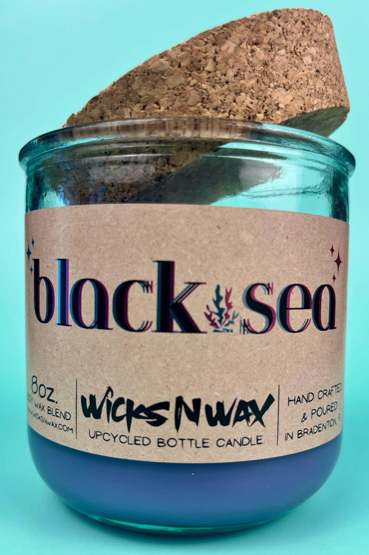Recycled glass candle in blue glass jar with cork lid, label on front