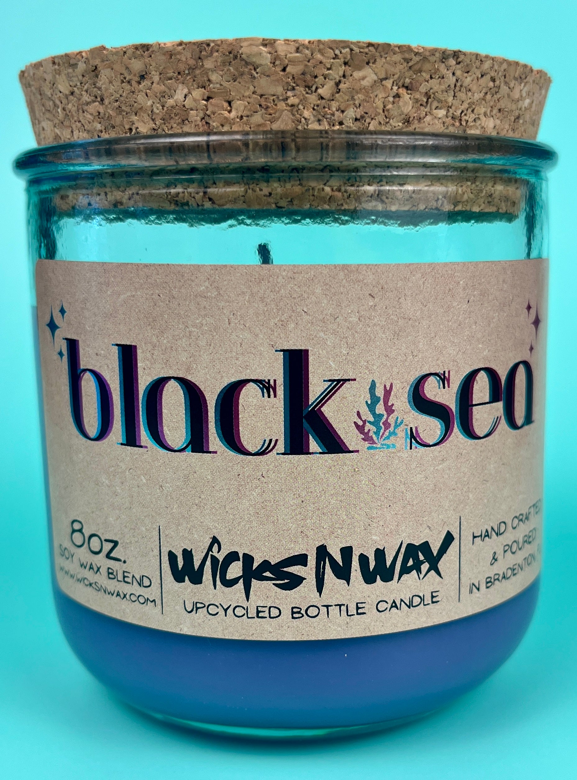 Recycled glass candle in blue jar with cork lid, front label visible