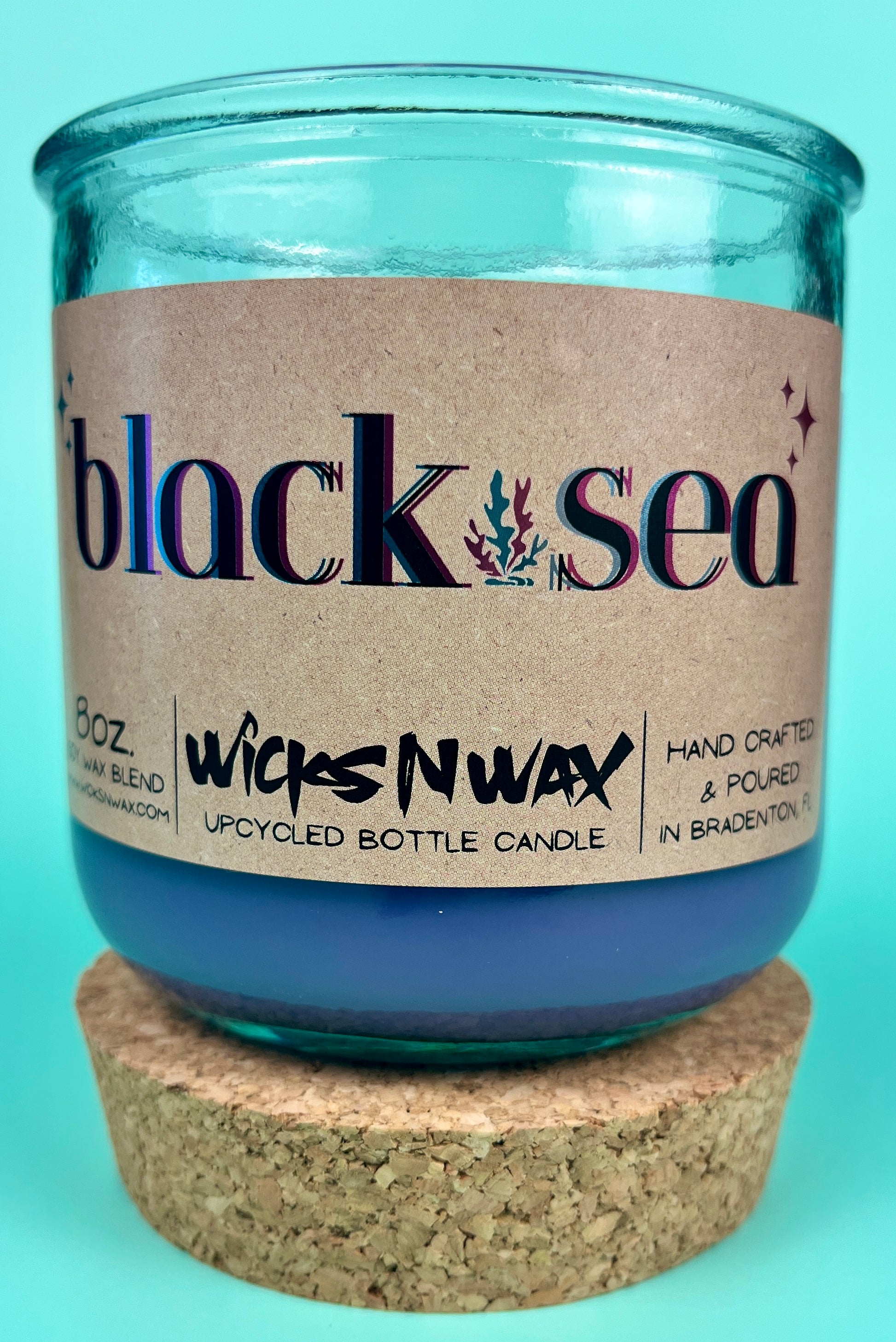 Recycled glass candle in blue glass jar with cork lid, label centered