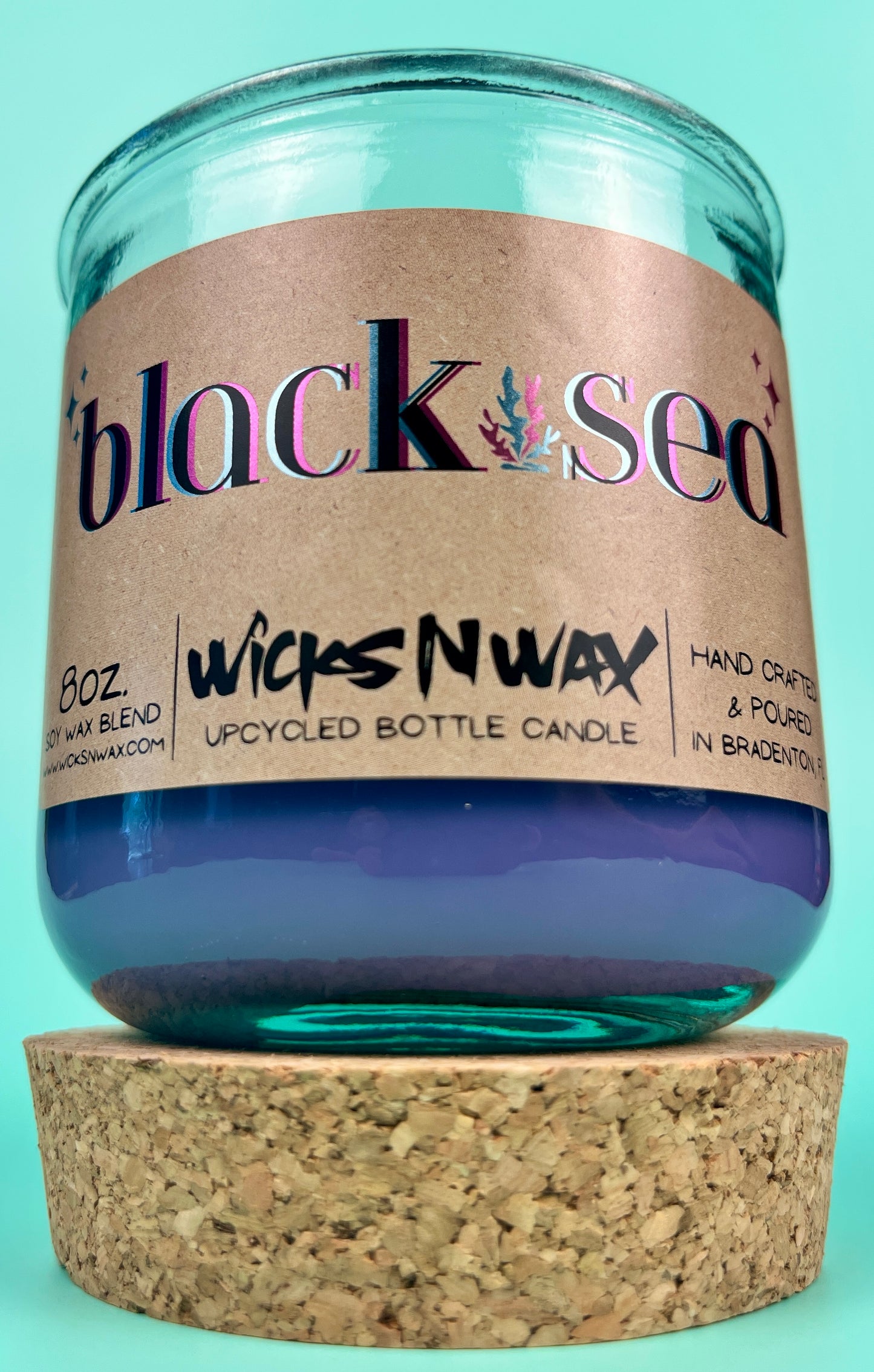 Recycled glass candle in blue jar with cork lid on bottom, front label visible