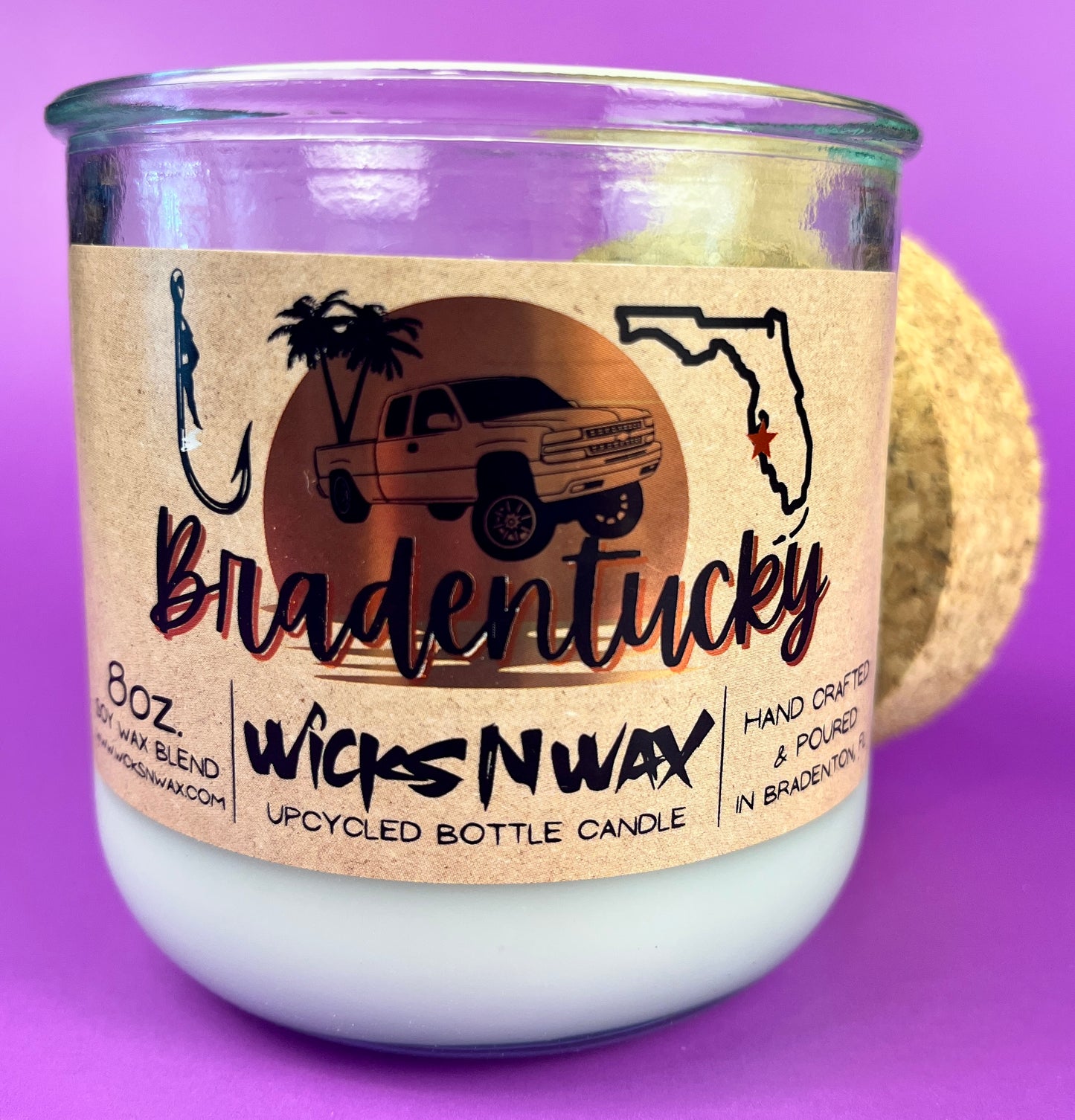 Recycled glass candle in clear jar with white wax and beige wrap label, showing artwork.
