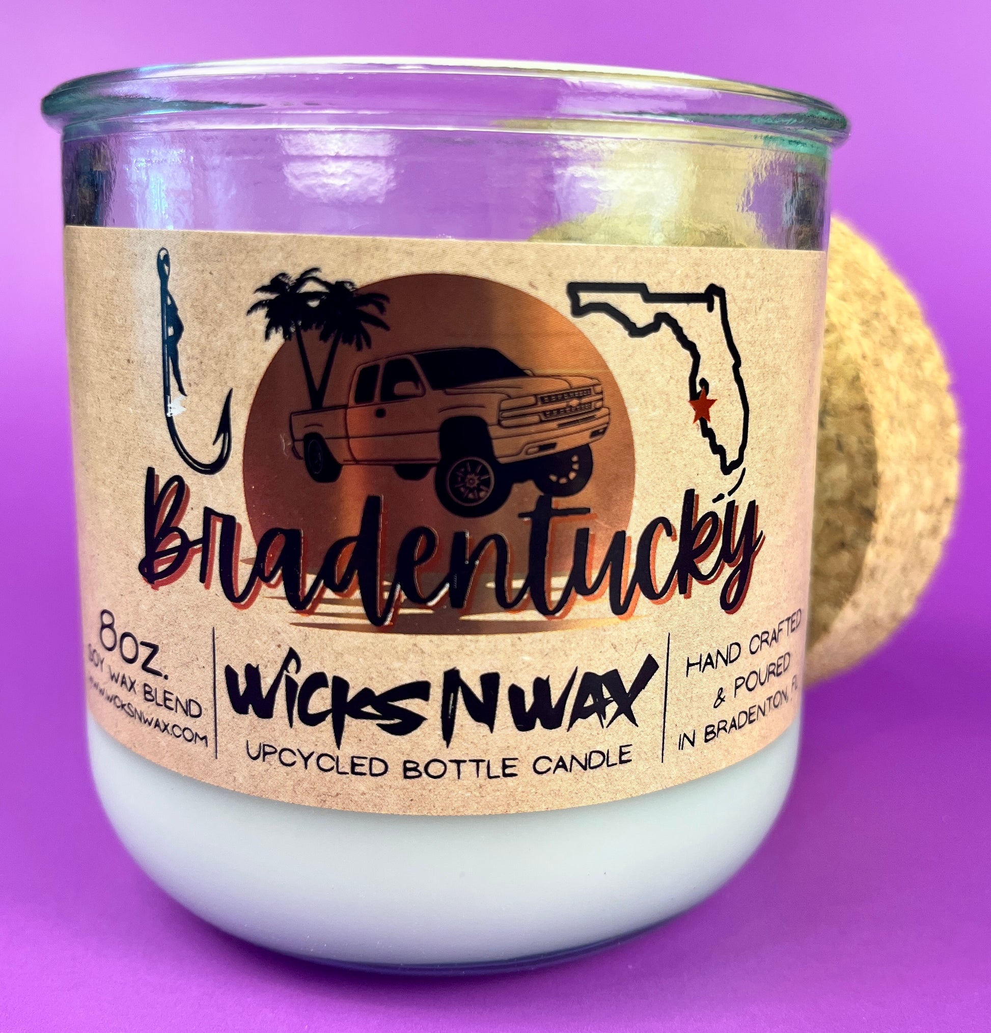 Recycled glass candle in clear jar with white wax and beige wrap label, showing artwork.