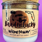 Recycled glass candle in clear jar with white wax and beige printed label, cork base visible.