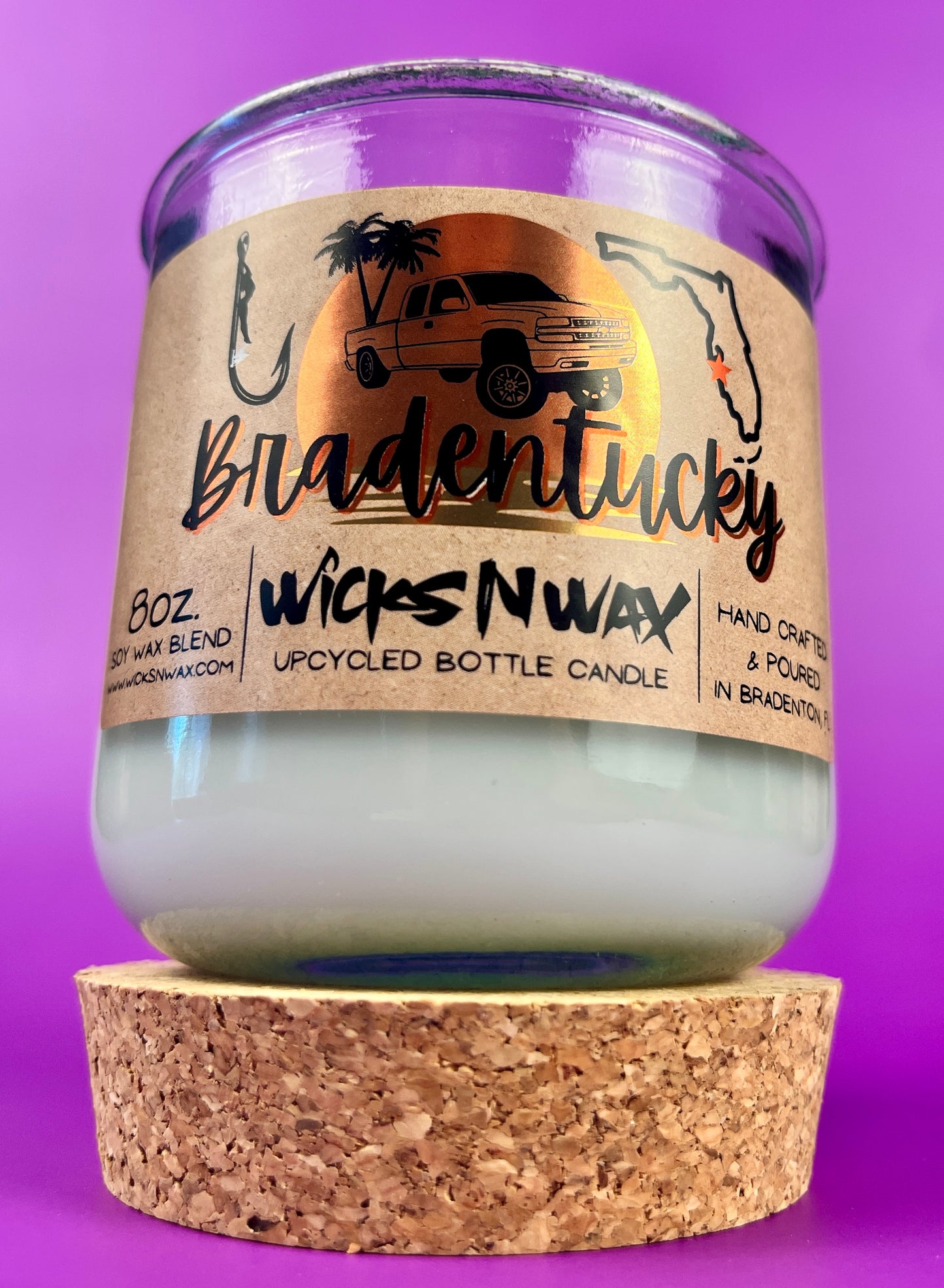 Recycled glass candle in clear jar with white wax and beige label, shown with cork base.
