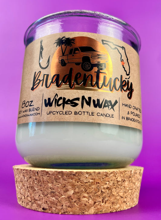 Recycled glass candle in clear jar with white wax and beige label, shown with cork base.