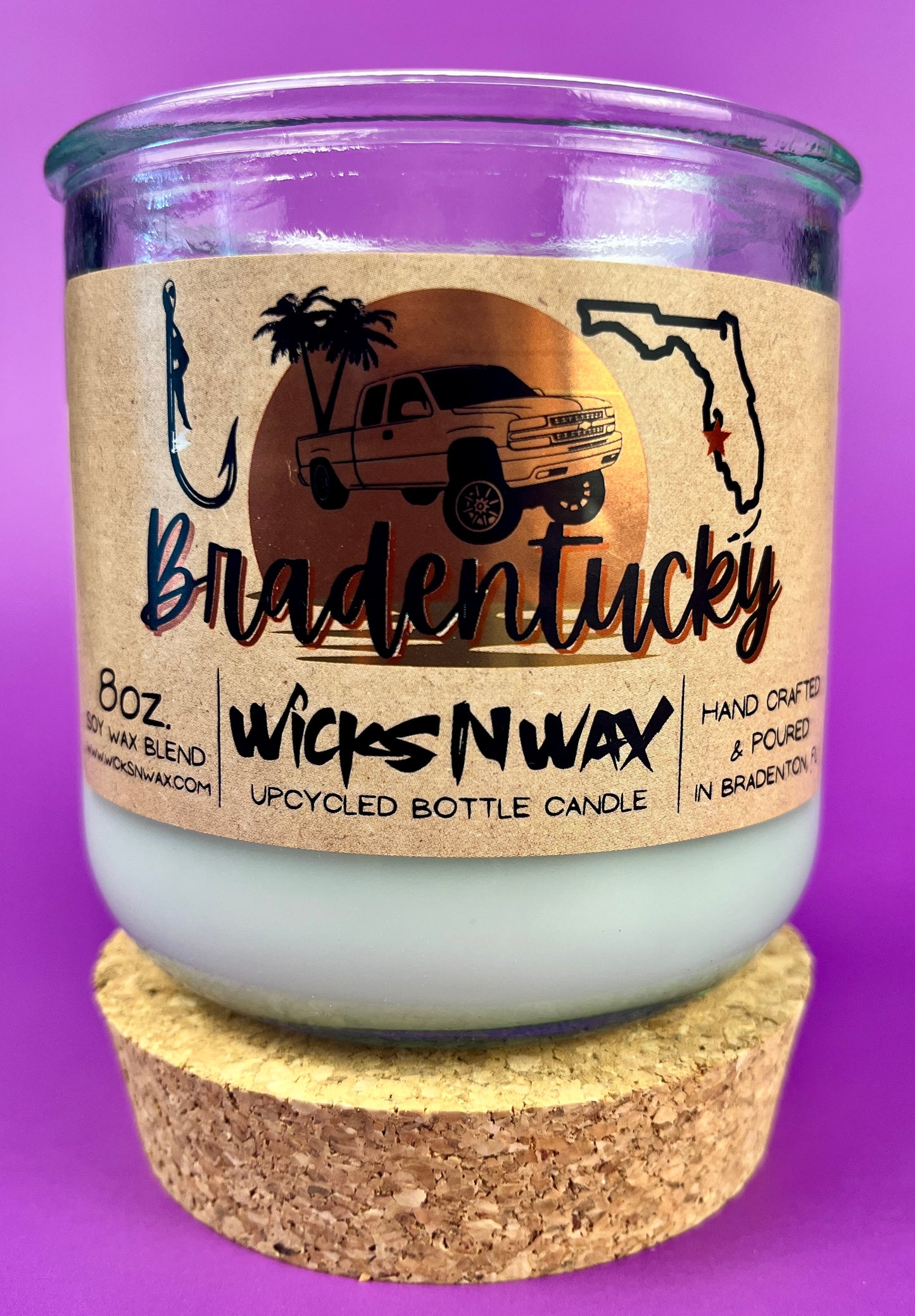 Recycled glass candle in clear jar with white wax and beige label on cork base.