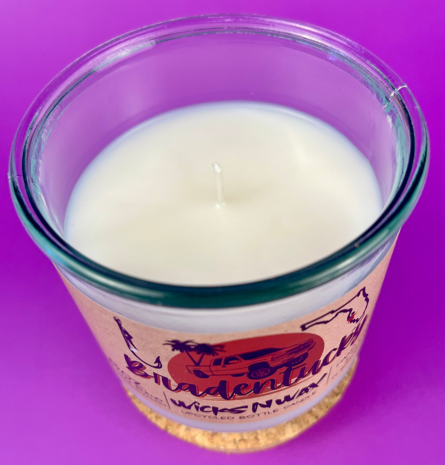 Recycled glass candle top view with white wax surface and central wick inside clear jar.