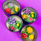 Small cactus art tin set with four cups showing pink, purple, yellow, and green wax