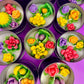 Set of small candle tins with colorful flower wax designs in metal lids