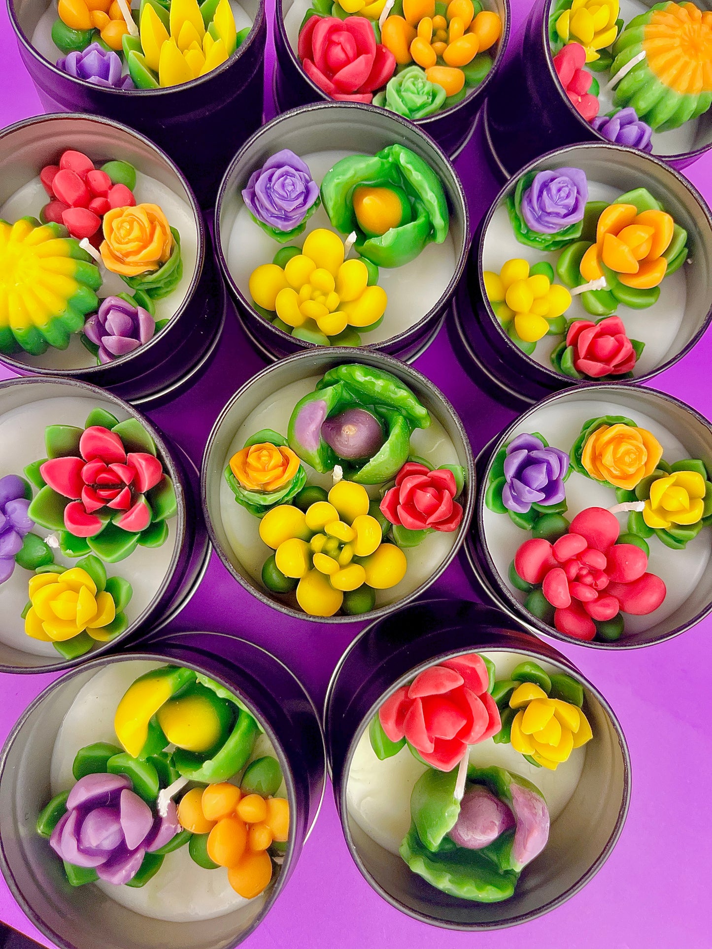 Set of small candle tins with colorful flower wax designs in metal lids