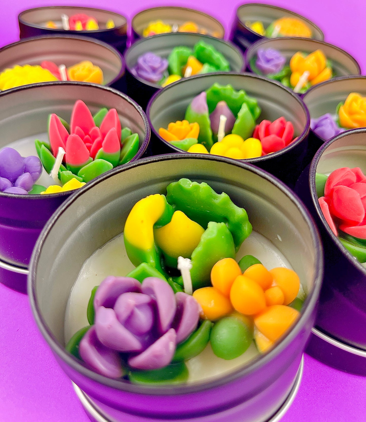 Small candle tin with green leaves, yellow and purple flowers, and pink rose