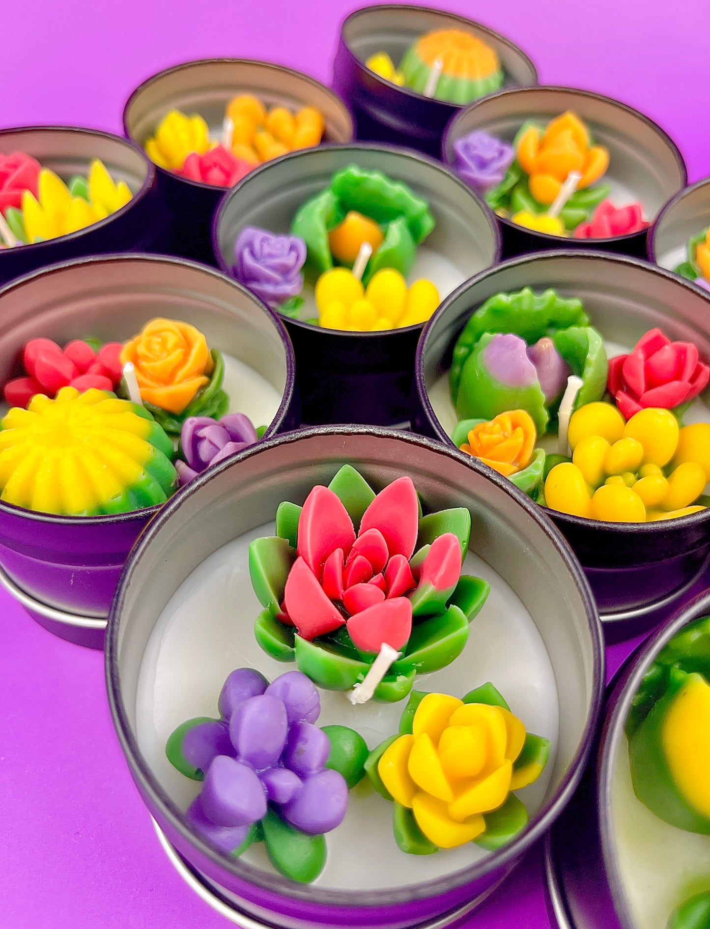 Small candle tin with green leaves, purple flowers, yellow accents, and pink rose