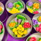 Small candle tin set with green, yellow, purple, and orange flower wax pieces
